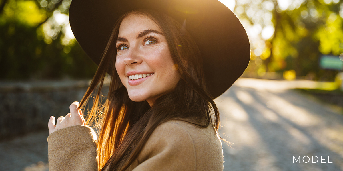 Smiling model with wide brim hat in the outdoors | emmett plastic surgery