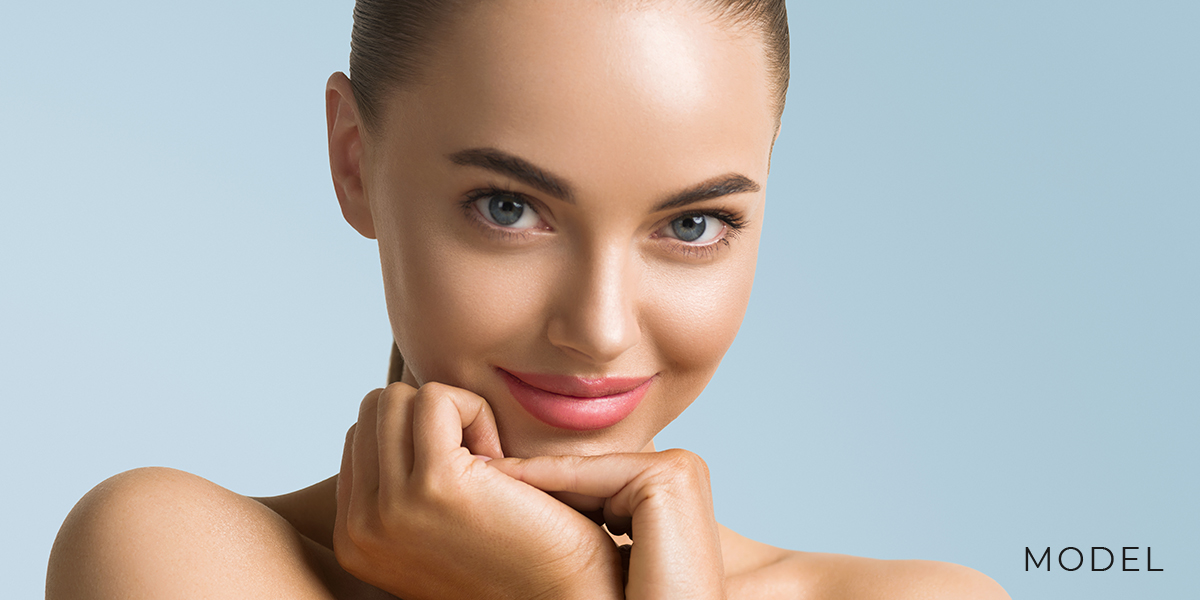 Model resting her face on hands | emmett plastic surgery