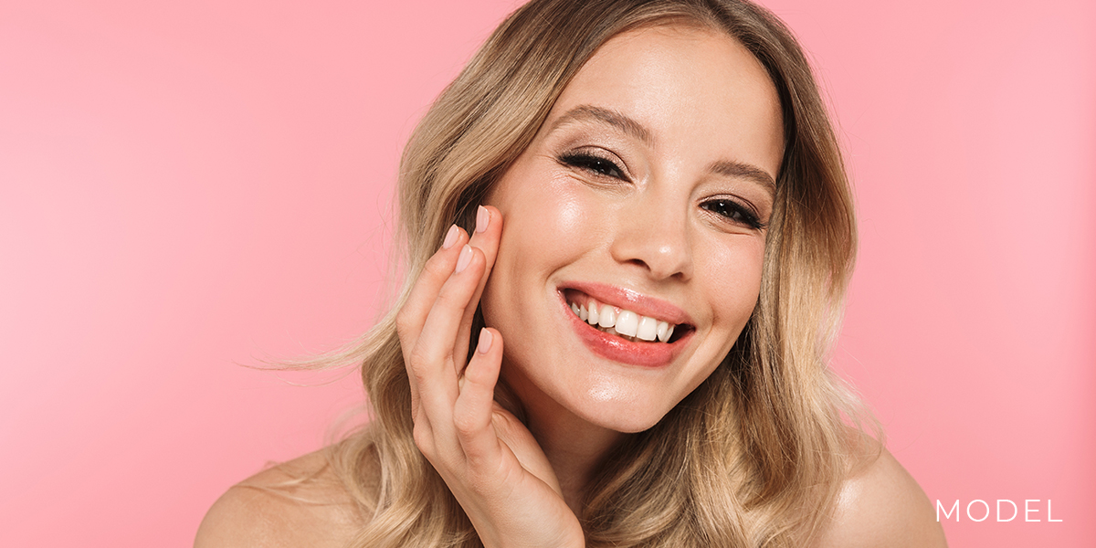 Model Smiling Against Pink Background