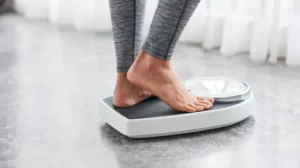 Person weighing themselves on scale | emmett plastic surgery