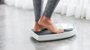 Person weighing themselves on scale
